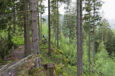 Hiker standing on rock looking at view in forest - GWF07309