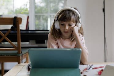 Blondes Mädchen mit Hand auf der Wange e-learning über Tablet-PC zu Hause - TYF00066