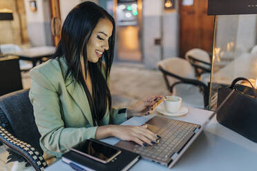 Lächelnder Freiberufler beim Online-Shopping am Laptop im Café - JRVF02730