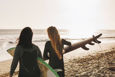 Frauen mit Surfbrettern gehen am Strand zum Ufer, Gran Canaria, Kanarische Inseln - MRRF01880