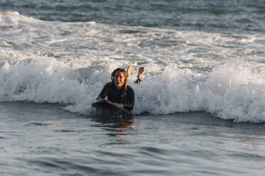 Frau beim Surfen im Meer auf dem Surfbrett liegend, Gran Canaria, Kanarische Inseln - MRRF01888