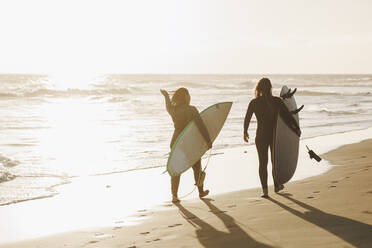 Frauen mit Surfbrettern bei Sonnenuntergang am Strand, Gran Canaria, Kanarische Inseln - MRRF01895