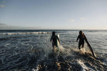 Frauen mit Surfbrettern beim Spaziergang im Meer, Gran Canaria, Kanarische Inseln - MRRF01896