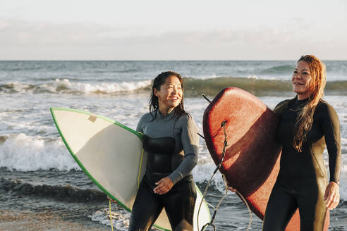 Surfer im Neoprenanzug mit Surfbrettern am Strand, Gran Canaria, Kanarische Inseln - MRRF01897