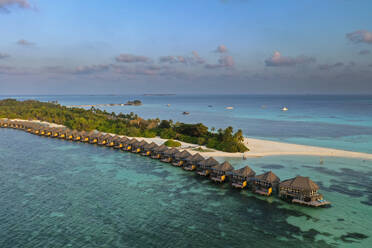 Maldives, Lhaviyani Atoll, Kuredu, Helicopter view of row of coastal bungalows at dawn - AMF09384