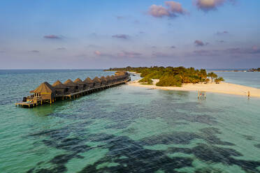 Maldives, Lhaviyani Atoll, Kuredu, Helicopter view of row of coastal bungalows at dawn - AMF09386