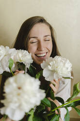 Happy woman with peony flowers at home - SEAF00495