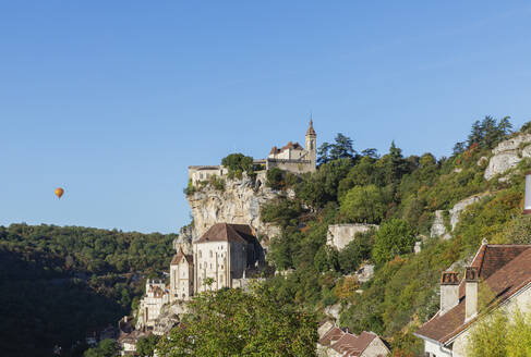 Frankreich, Lot, Rocamadour, Blick auf Felsenstadt mit Heißluftballon im Hintergrund - GWF07319