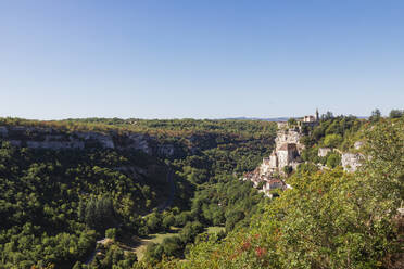 France, Lot, Rocamadour, View of Alzou Canyon in summer with clifside town in background - GWF07321