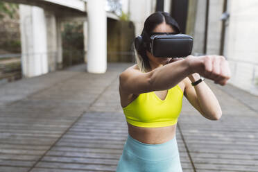 Sports woman with VR glassed boxing on footpath - JCCMF05252