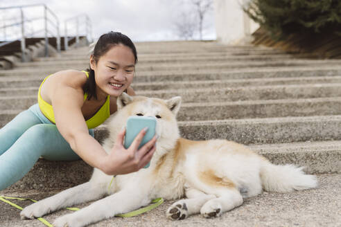 Lächelnde Frau nimmt Selfie mit Hund auf Smartphone - JCCMF05263