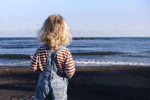 Junge mit blondem Haar bewundert das Meer am Strand - ASGF02108