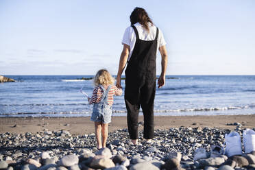 Vater und Sohn halten sich am Strand an den Händen - ASGF02110