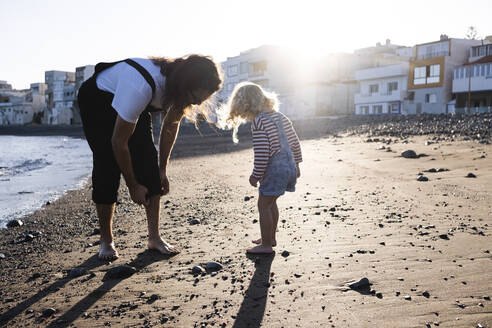 Father and son playing by coastline at beach - ASGF02115