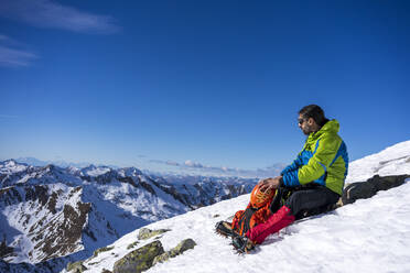 Ein Mann ruht sich auf einem verschneiten Berg in den Orobischen Alpen in Valtellina, Italien, aus - MCVF00951