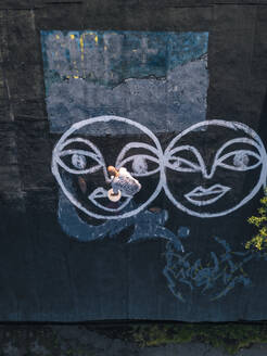 Maler malt Smiley-Graffiti auf das Dach - KNTF06557