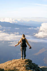 Carefree tourist standing at cliff on mountain at Caucasus Nature Reserve in Sochi, Russia - OMIF00600