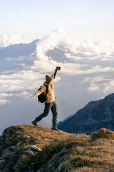 Woman with arms outstretched walking at edge of mountain at Caucasus Nature Reserve in Sochi, Russia - OMIF00602