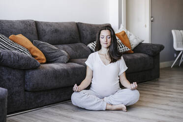 Schwangere Frau meditiert zu Hause - EBBF05632