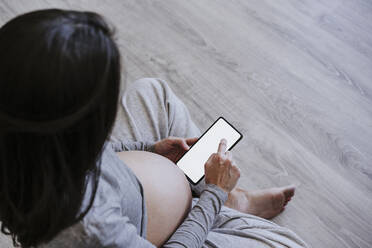 Schwangere Frau benutzt Smartphone zu Hause - EBBF05640