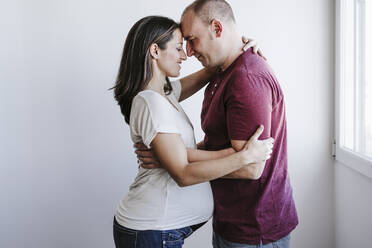 Mann umarmt schwangere Frau zu Hause - EBBF05660