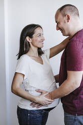 Happy man looking at pregnant woman at home - EBBF05661