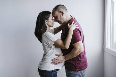Pregnant woman embracing man at home - EBBF05665