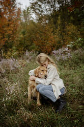 Blond girl hugging Labrador Retriever in garden - ELEF00006