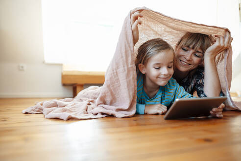 Lächelnder Sohn verwendet Tablet-PC mit Mutter unter Schal zu Hause - JOSEF07041