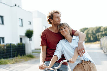 Thoughtful man and woman with bicycle on footpath - JOSEF07051