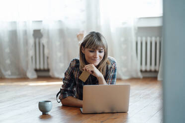 Lächelnde Frau beim Online-Shopping auf dem Laptop zu Hause - JOSEF07053