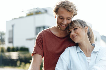 Smiling affectionate couple in front of house - JOSEF07057