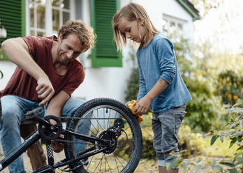 Father helping son repairing bicycle in backyard - JOSEF07063