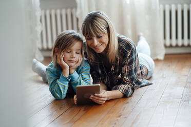 Lächelnde Mutter und Sohn sehen sich zu Hause gemeinsam einen Tablet-PC an - JOSEF07074
