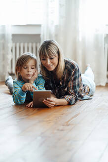 Sohn zeigt auf digitales Tablet mit Mutter auf dem Boden liegend zu Hause - JOSEF07077