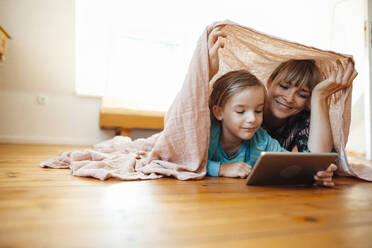 Mother and son below shawl watching tablet PC at home - JOSEF07094