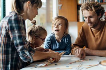 Eltern mit zwei Kindern spielen Mikado zu Hause - JOSEF07099