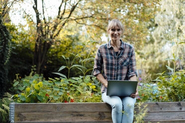 Frau mit Laptop im Bio-Hinterhof - JOSEF07121