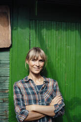 Smiling woman with arms crossed in front of wall - JOSEF07125