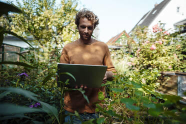 Young man using laptop in back yard - JOSEF07140