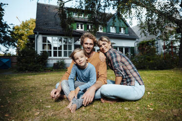 Smiling parents with son sitting outside house - JOSEF07148
