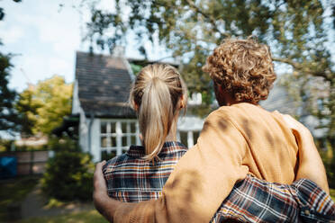 Paar, das sich umarmt und ein Haus betrachtet - JOSEF07155