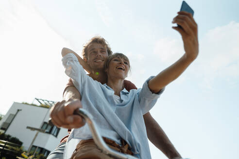 Glückliches Paar auf dem Fahrrad nimmt Selfie durch Smartphone - JOSEF07166
