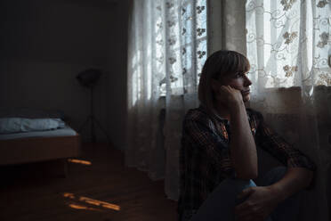 Woman contemplating by curtains in bedroom at home - JOSEF07175