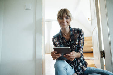 Lächelnde Frau mit Pony hält digitales Tablet zu Hause - JOSEF07186