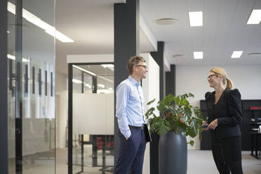 Lächelnder Geschäftsmann im Gespräch mit einem Kollegen in einer Bürobesprechung - JAHF00106