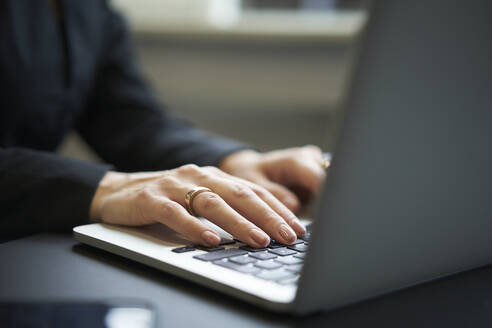 Businesswoman's hands typing on laptop in office - JAHF00125