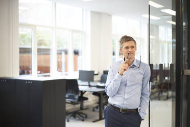 Businessman with eyeglasses standing at office - JAHF00137