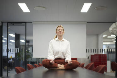 Geschäftsfrau meditiert im Konferenzraum - JAHF00143