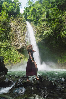 Frau steht auf einem Felsen vor dem La Fortuna Wasserfall, Costa Rica - RSGF00850